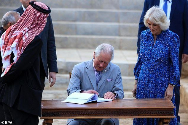 웨일즈 왕자는 그의 아내인 콘월 공작부인인 카밀라가 지켜보는 가운데 방명록에 서명하고 있습니다(사진).