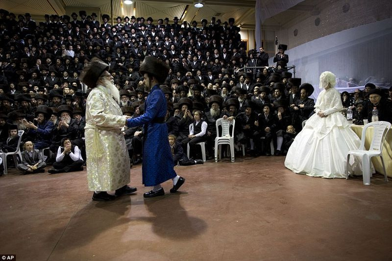 Rabid ja peigmees tantsivad, et täita tseremoonia mitsva tantsi osa, samal ajal kui pealtvaatajad pulmast pilte teevad