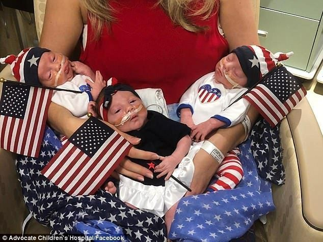 놀기: 세 쌍둥이의 엄마가 자신의 애국적인 빨간 셔츠를 입고 세 아기를 안고 있는 사진이 찍혔습니다.