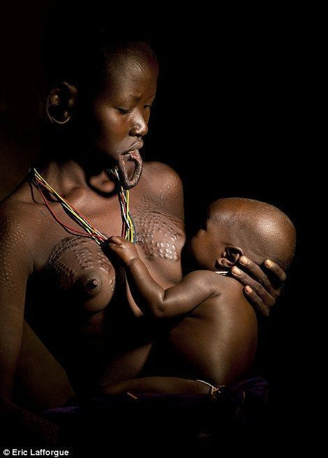 아기에게 젖을 먹이는 동안 흉터 패턴을 보여주는 Surma 어머니