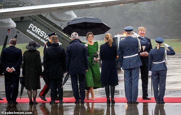 네덜란드의 막시마 여왕은 우산 아래에서 비를 피해야 했음에도 불구하고 씩씩한 표정을 짓고 있습니다(사진).