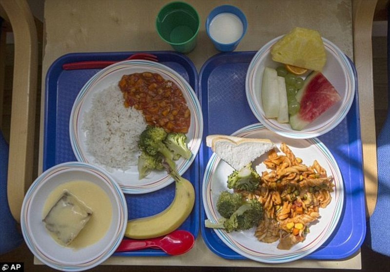 더 건강한 영국 학교 저녁 식사: 런던의 한 초등학교에서 두 쟁반. 오른쪽의 식사는 브로콜리를 곁들인 파스타와 빵 한 조각, 과일로 구성되어 있습니다. 왼쪽은 쌀과 브로콜리를 곁들인 야채 칠리, 커스터드를 곁들인 스폰지 케이크, 바나나